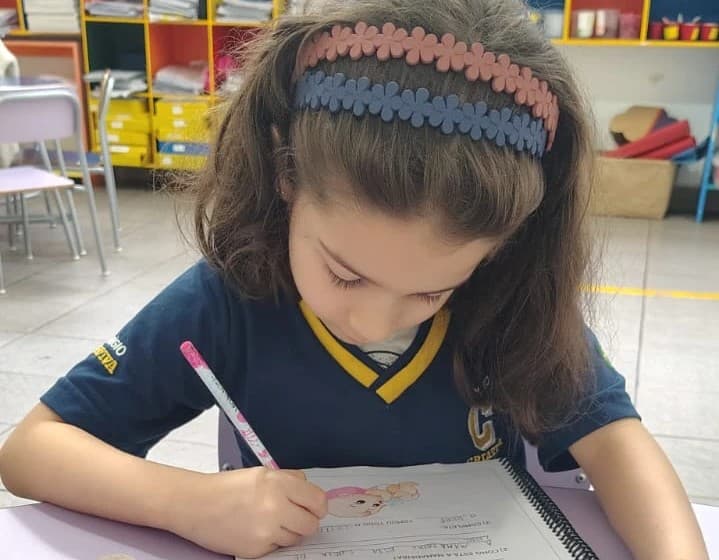 Aluna escreve com atenção na ficha de interpretação de texto, na carteira