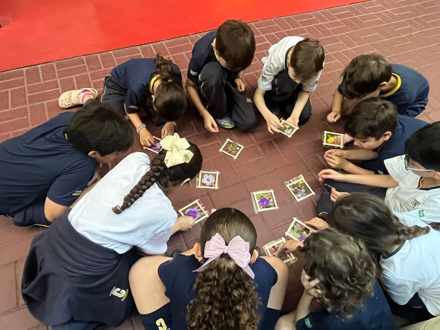 Alunos sentados em roda, vistos de cima, montando juntos um jogo de cartões com flores