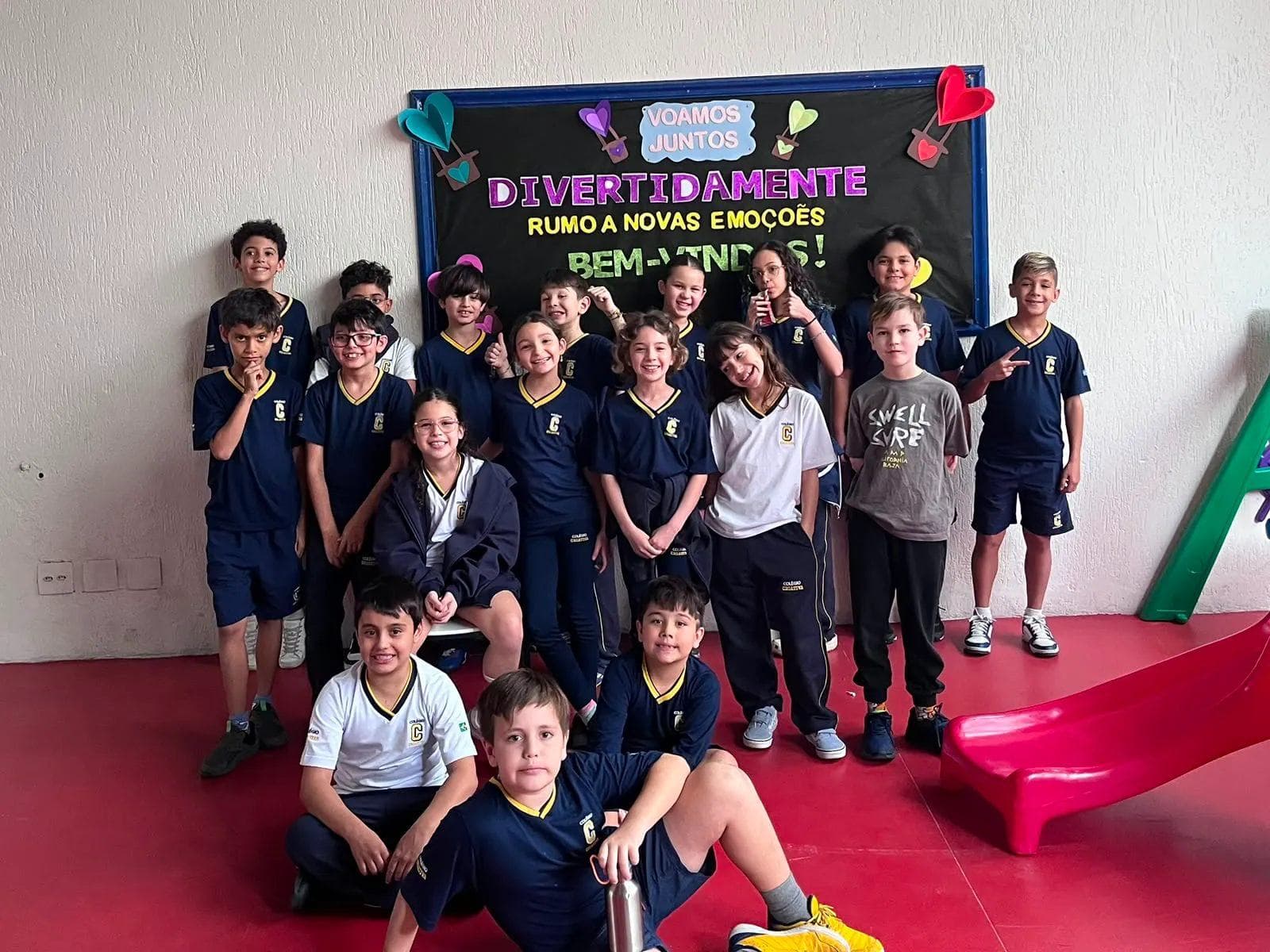 Turma do Fundamental I reunida e sorrindo diante do mural de boas-vindas da sala