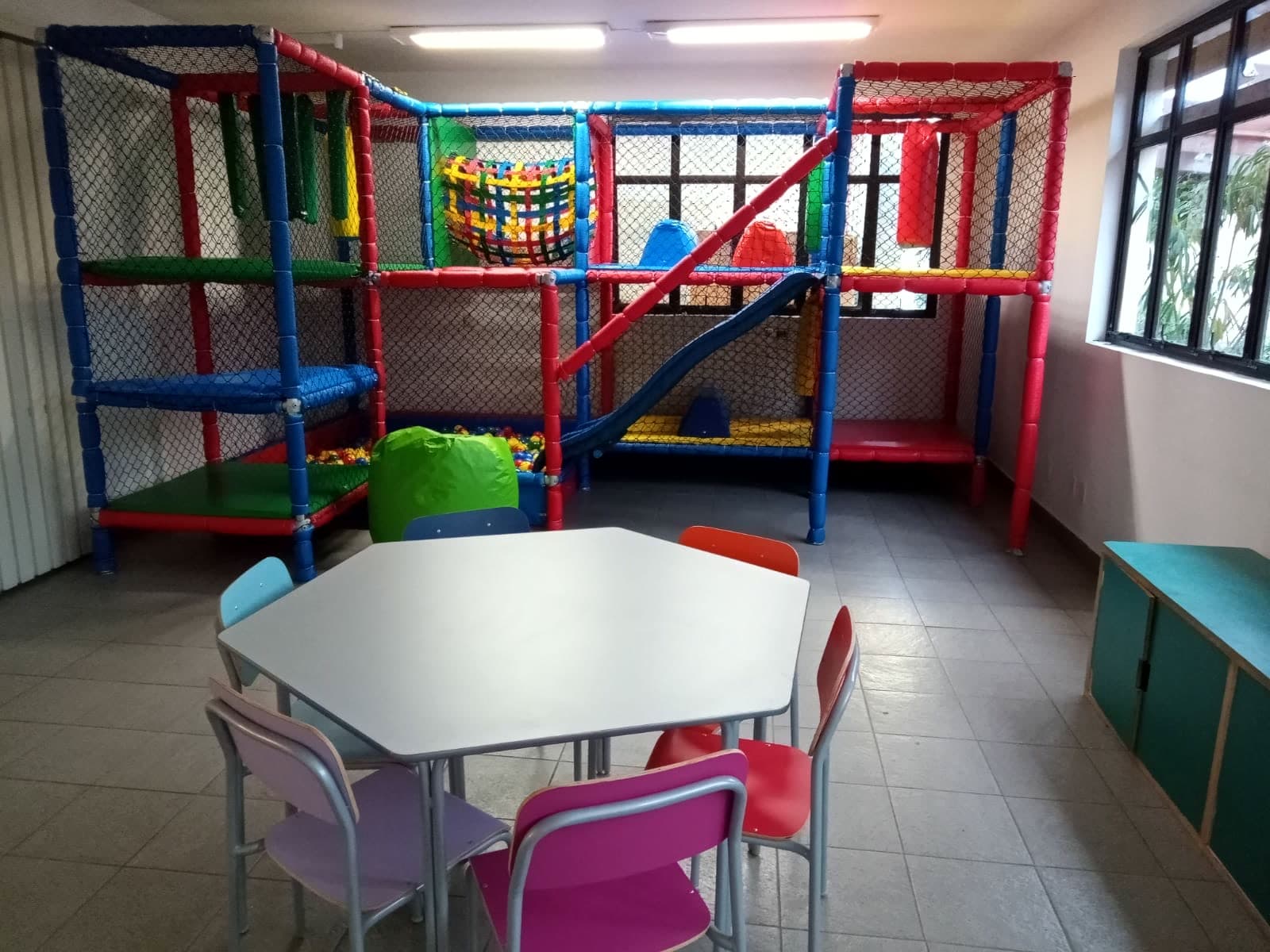 Espaço multifuncional com brinquedão e mesa para atividades do período integral