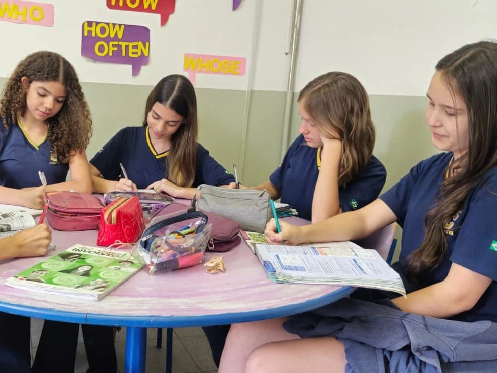 Alunas dos anos finais estudam inglês em grupo, em volta de uma mesa redonda
