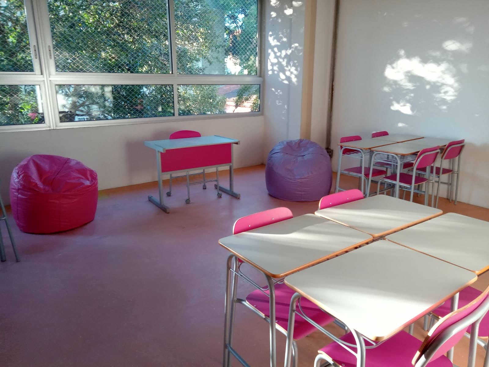 Sala ambiente com pufes coloridos, mesas baixas e janelas amplas